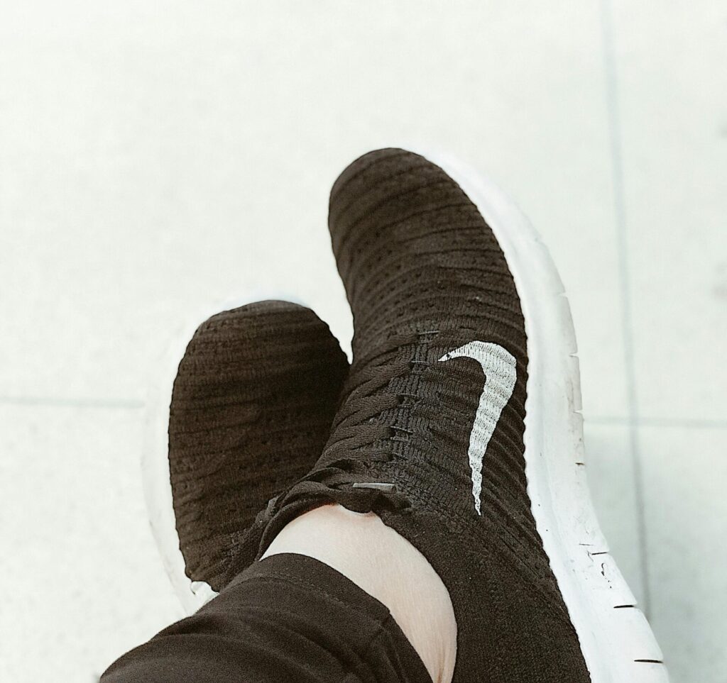 Close-up of black knit sneakers on pavement, showcasing casual fashion footwear.